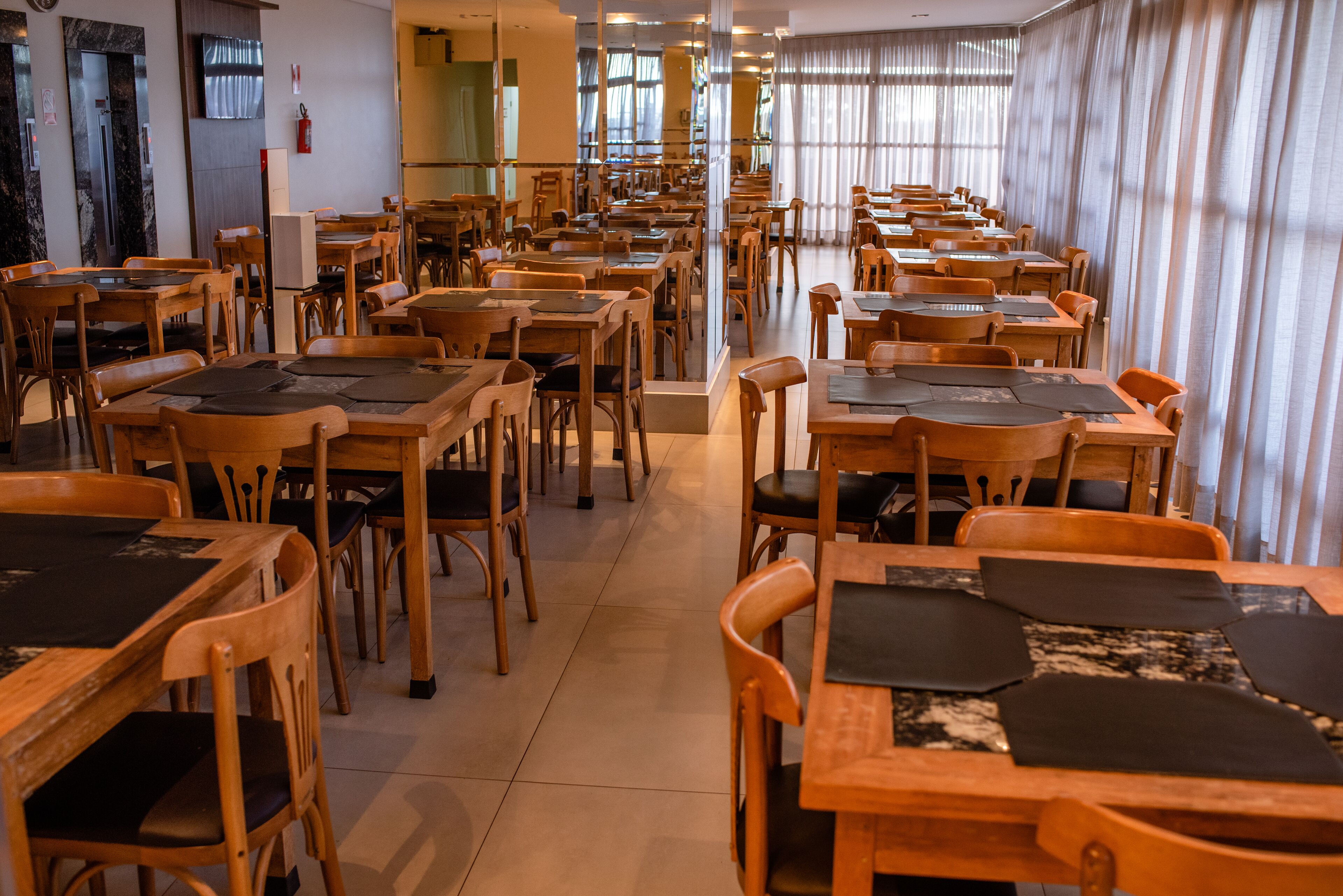 Un amplio comedor con varias mesas y sillas de madera, dispuestas en filas.