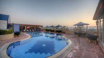 Relax by the pool with a view of the city skyline, surrounded by lounge chairs and umbrellas.