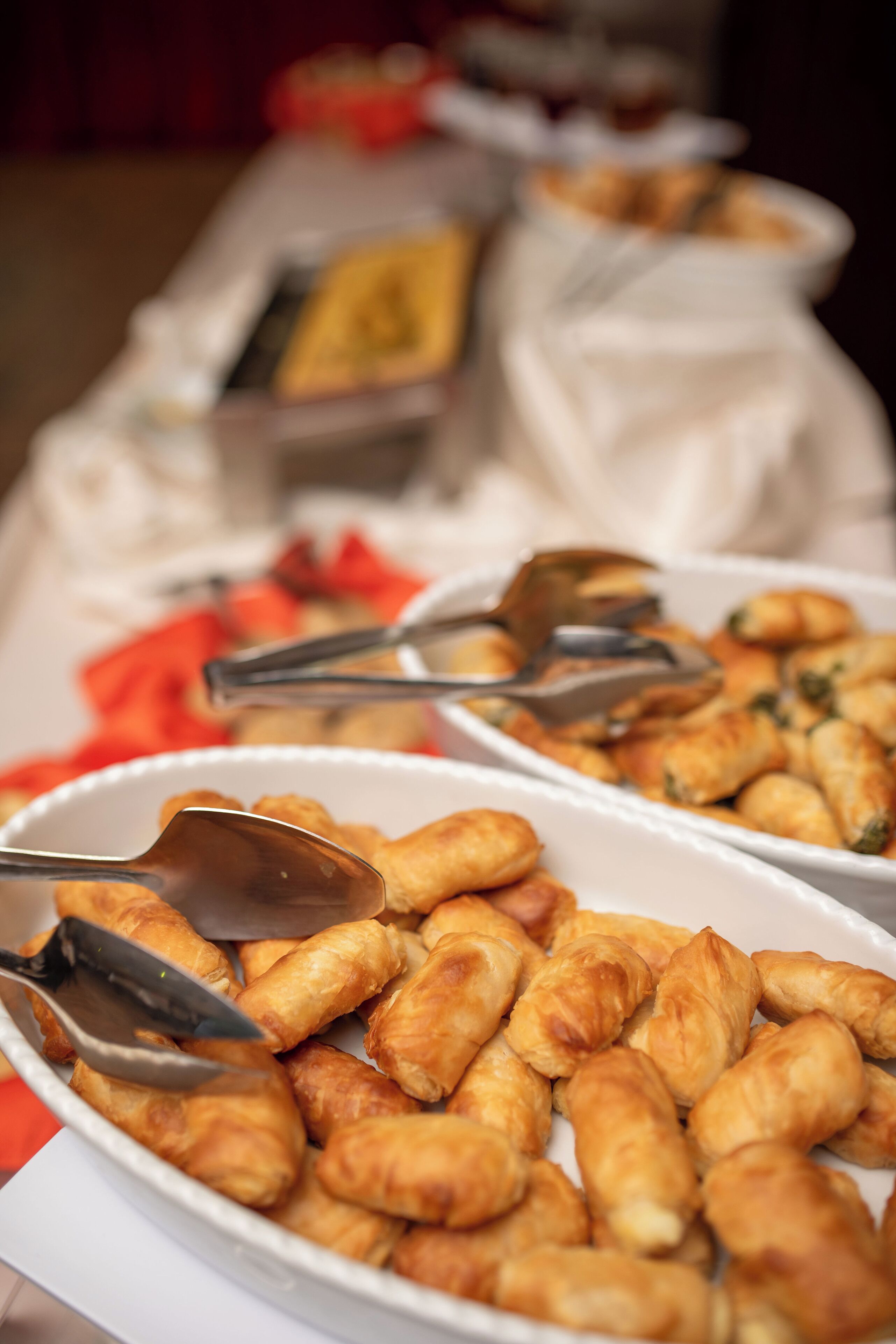 Una mesa de buffet con diversos alimentos, entre ellos pasteles y un plato con etiqueta amarilla.