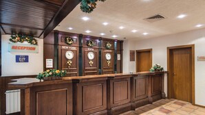 Una reception con un cartello 'RECEPTION', tre orologi etichettati 'NEW YORK', 'SOFIA' e 'LONDON', e un cartello che indica 'SAFE ROOM'.