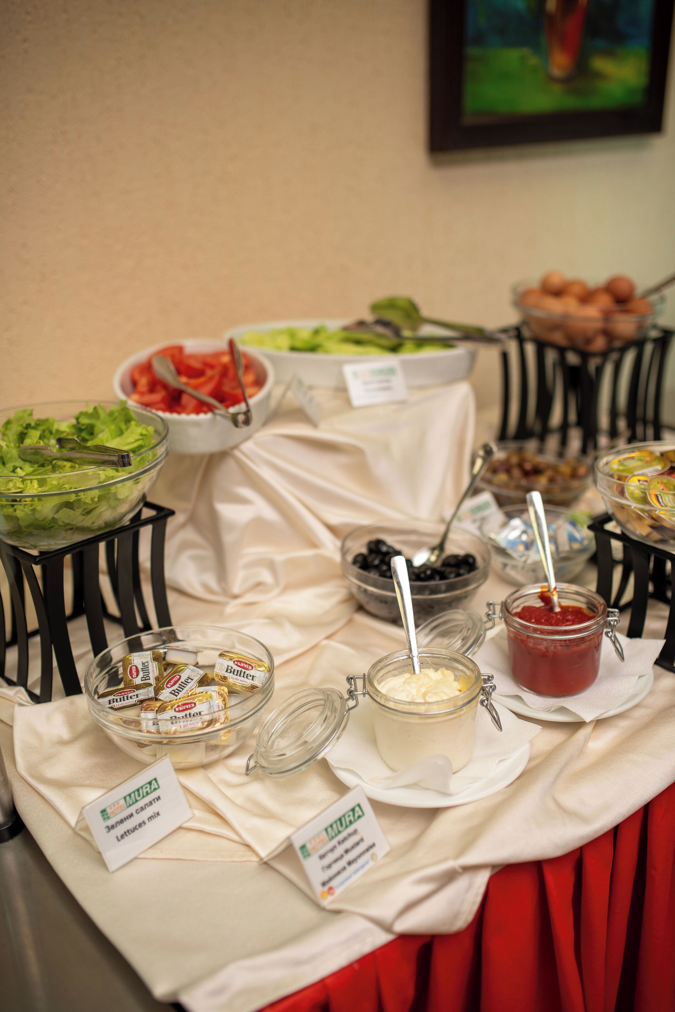 Een buffet met diverse soorten eten en sauzen, waaronder salades, fruit en spreads, met labels die de verschillende secties aanduiden.