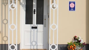 A white entrance with a decorative metal frame, a door with a keyhole, and a sign indicating guest accommodation. - Brentwood Hotel (Brentwood)