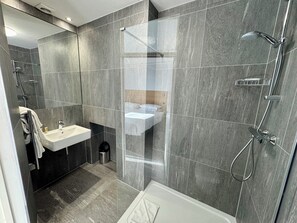 A modern bathroom with a shower, sink, and toilet. - Brentwood Hotel (Brentwood)