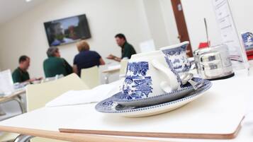 Una mesa de comedor con una taza y platillo de cerámica azul y blanco, un vaso de agua y un atril para el menú.