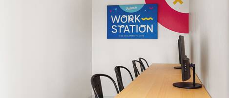 A conference room with a long table, black chairs, a computer, and a wall-mounted sign reading "WORK STATION".