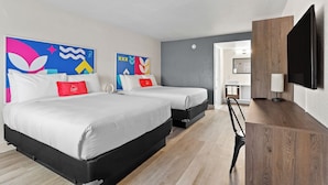Une chambre d’hôtel moderne avec deux lits, un bureau en bois, un téléviseur à écran plat et des œuvres d’art abstraites accrochées aux murs.