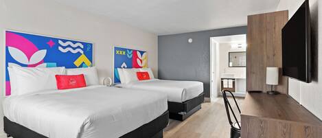 A modern hotel room with two beds, a wooden desk, a flat-screen TV, and abstract artwork on the walls.