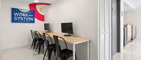 A modern work station area with a long table, black chairs, and two monitors.
