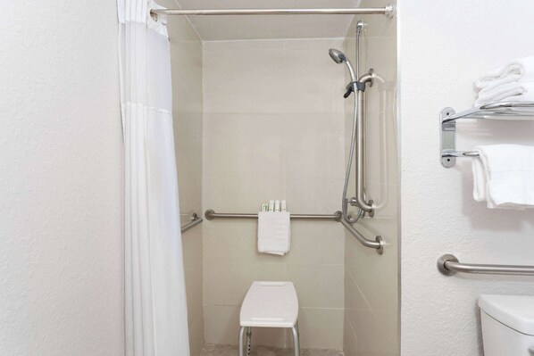 Un angolo doccia con porta in vetro, uno sgabello bianco e un portascopevoli con asciugamani piegati.