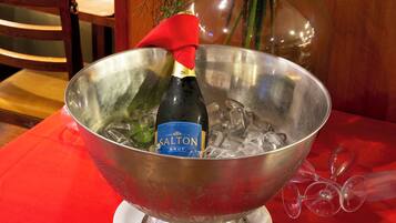 A metal bowl containing a bottle of Salton Brut champagne, ice, and empty wine glasses.