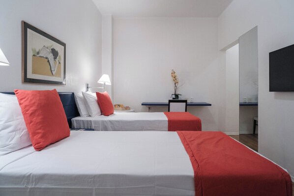 A hotel room with two beds, a desk, a chair, a TV, and a framed picture on the wall. - Hotel Normandie by Easy Plus (São Paulo)