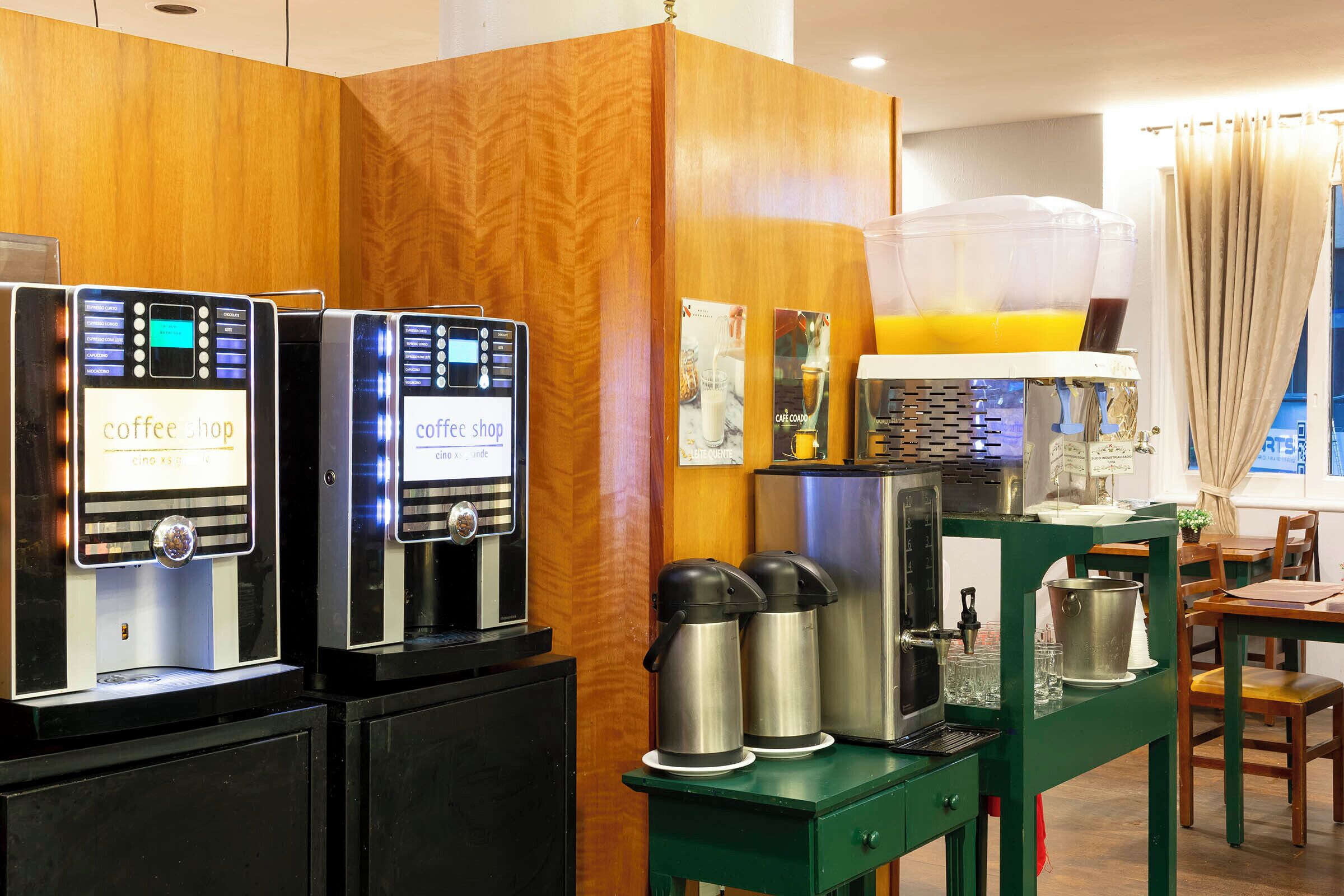A coffee shop area with espresso machines, a coffee station, and a dining table with chairs.