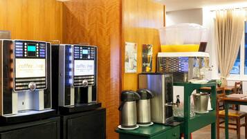 A coffee shop area with espresso machines, a coffee station, and a dining table with chairs.