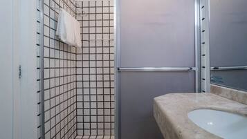 A bathroom with a tiled shower, a sink, and a mirror.