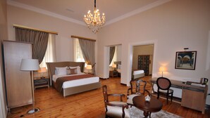 Quarto de hotel com uma cama grande, uma escrivaninha, uma cadeira, uma mesa de jantar e um candelabro.