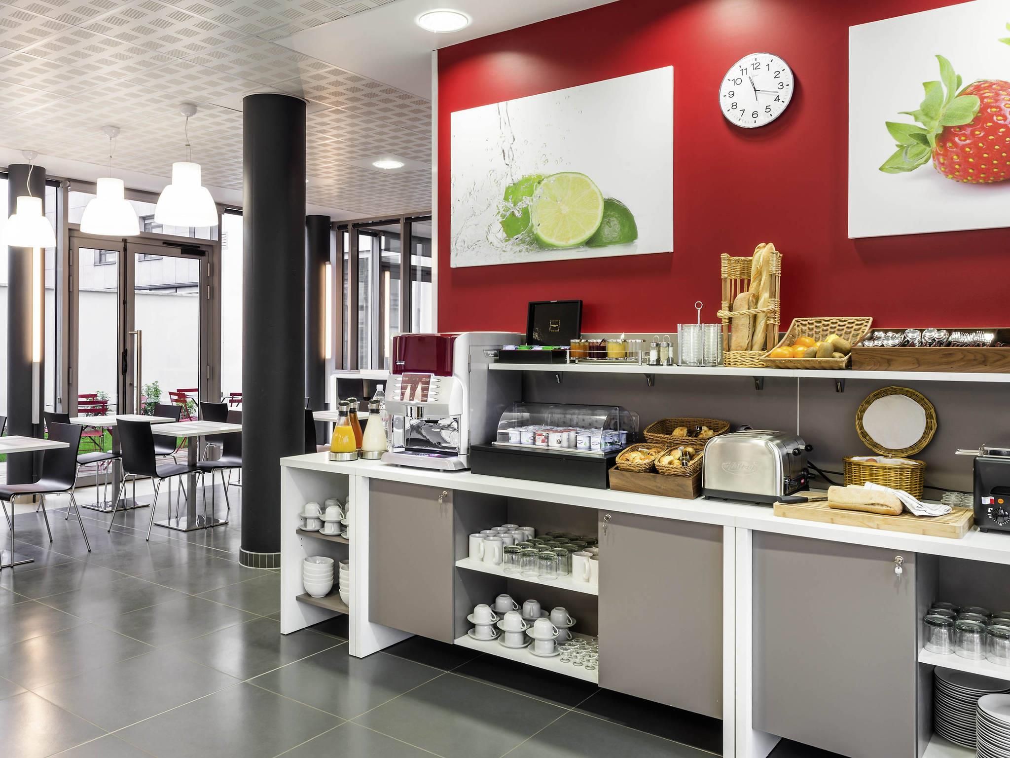 A modern cafe with a red accent wall, a clock, and various food and drink items displayed.
