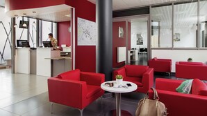 A modern hotel lobby with red seating, a reception desk, and a large map on the wall. - Aparthotel Adagio Access Paris Clichy (Clichy)