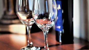 Two wine glasses on a wooden table with a wine bottle in the background.