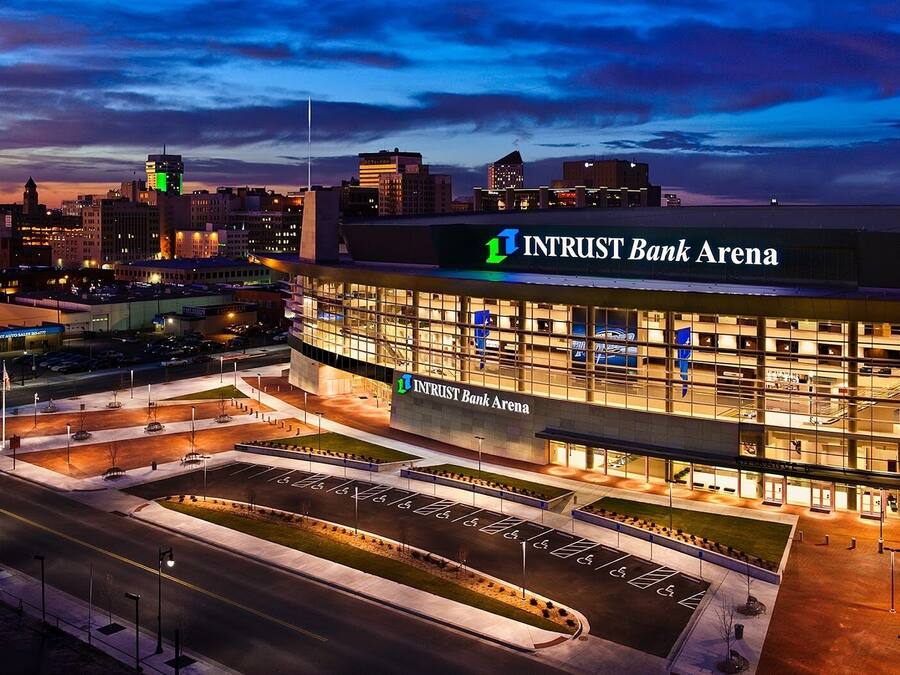A modern building with a sign reading "Intrust Bank Arena" and a parking lot with marked spaces.