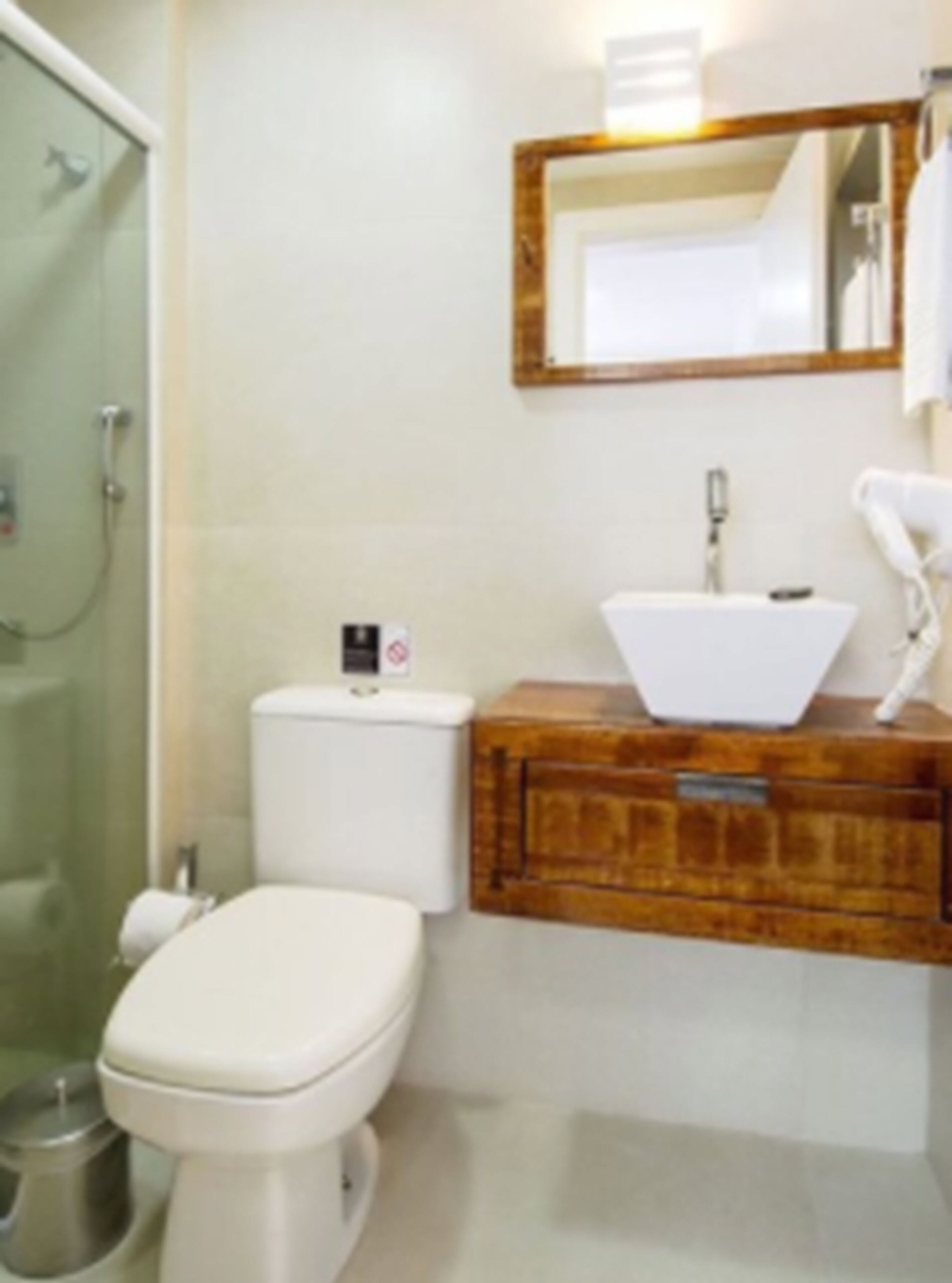 Une salle de bain comprenant des toilettes, un lavabo, un miroir et une douche.