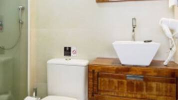 Une salle de bain comprenant des toilettes, un lavabo, un miroir et une douche.