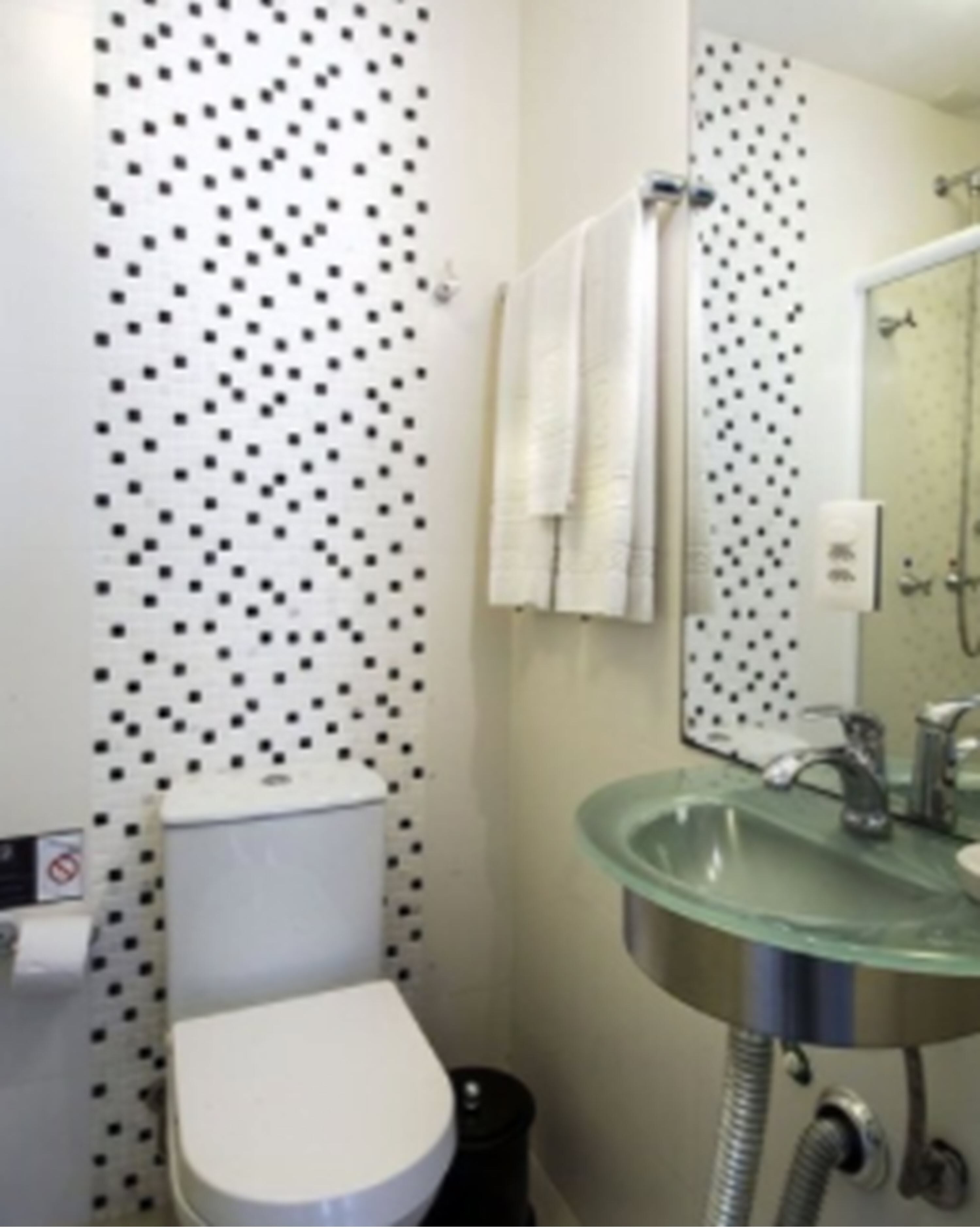A bathroom with a white toilet, a glass sink, and a mirror.