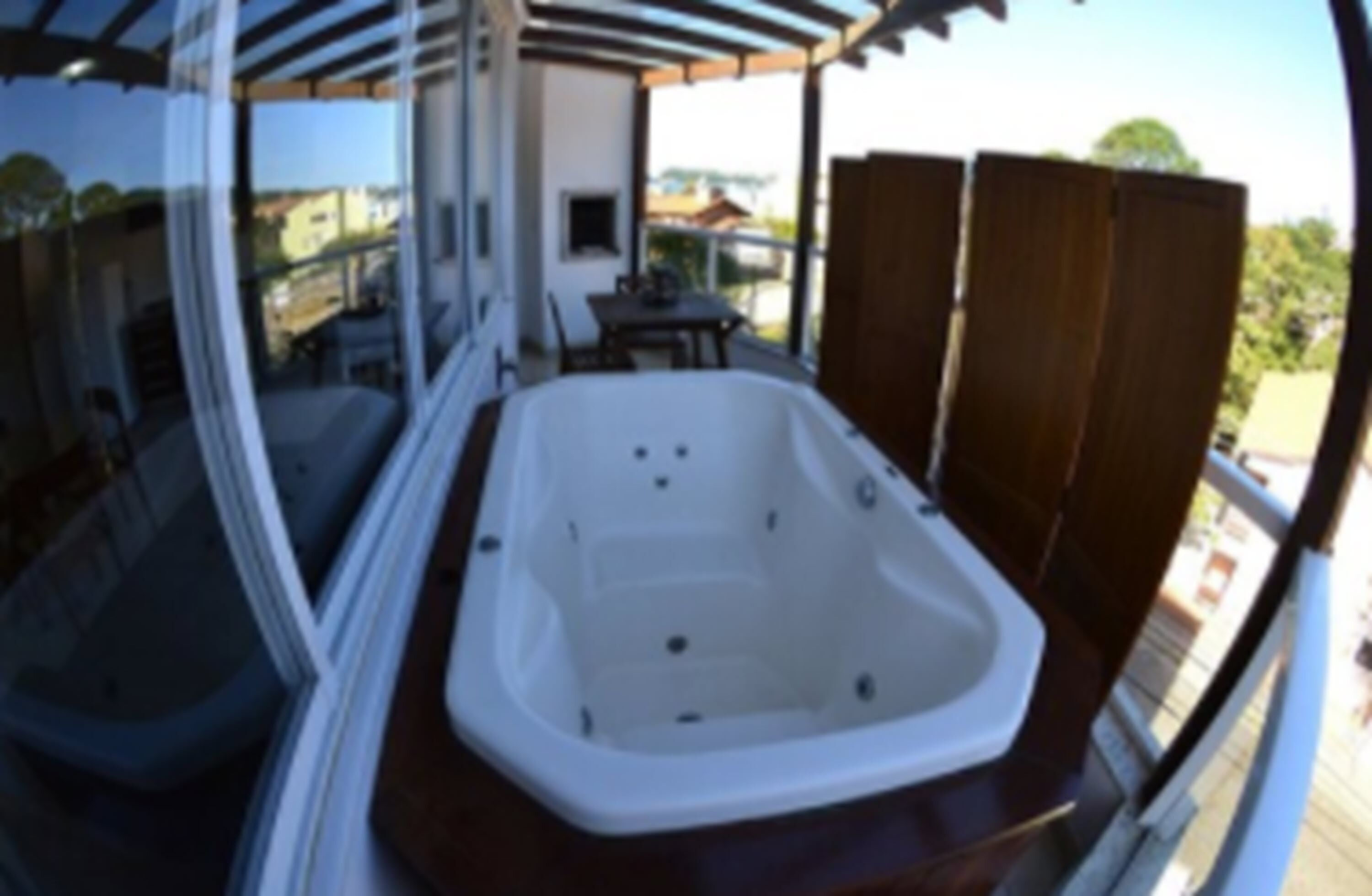 Een balkon met een hottub, een tafel en stoelen.