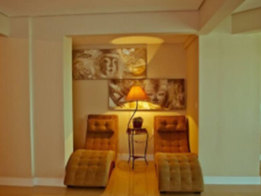 Una habitación con dos zonas de estar acolchadas, una lámpara de pie y una obra de arte en la pared.