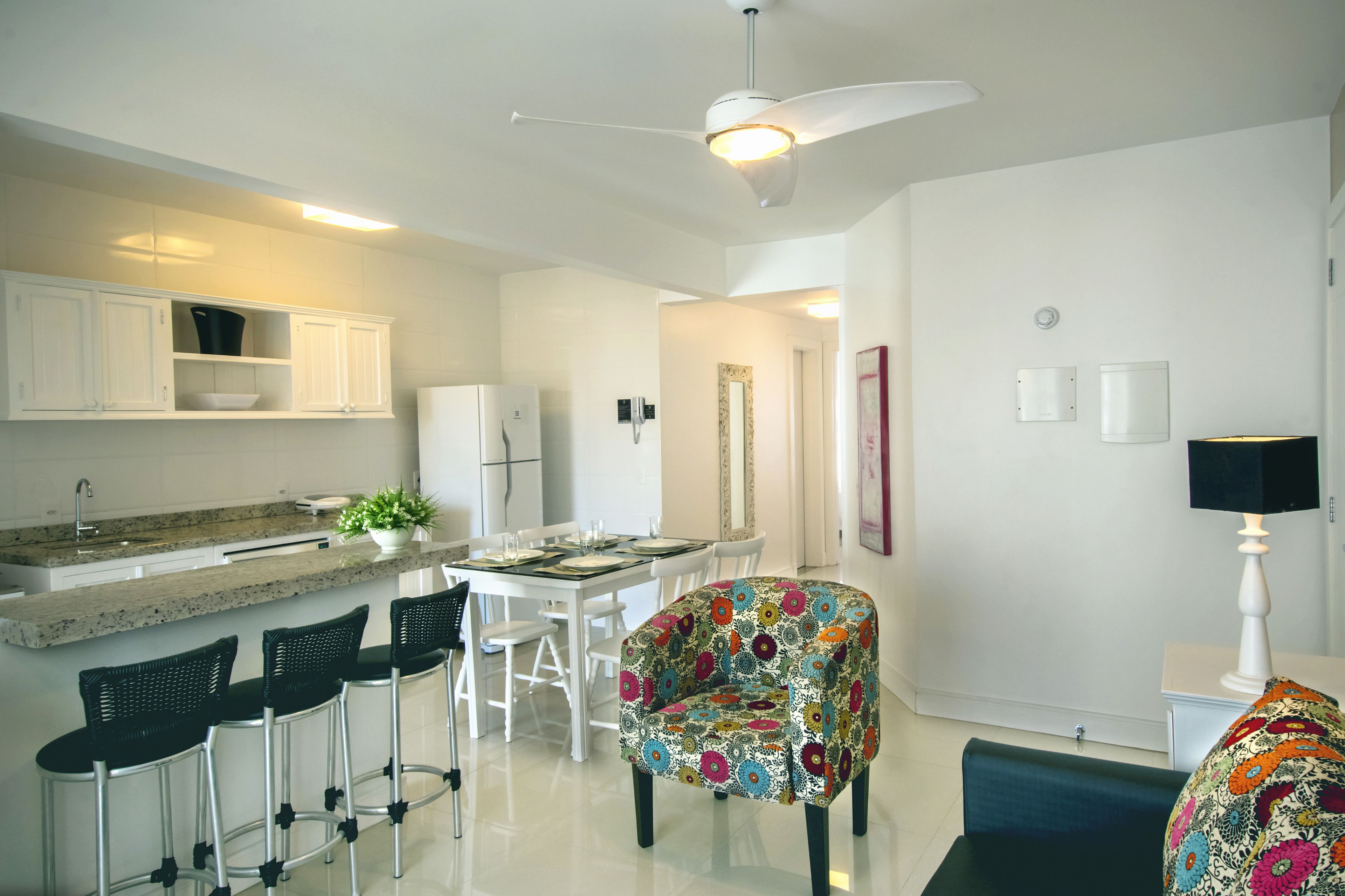 A modern kitchen with white cabinets, a granite countertop, and a bar area with black barstools.