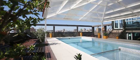 Una piscina al aire libre, sillones reclinables de piscina