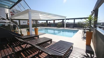 Una piscina al aire libre, sillones reclinables de piscina