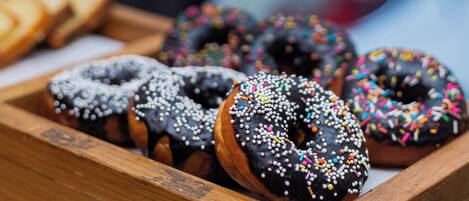 A wooden tray with assorted donuts, including chocolate and glazed varieties with sprinkles.