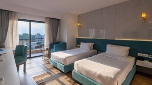 Una habitación de hotel moderna con dos camas, un escritorio y vistas a la ciudad.