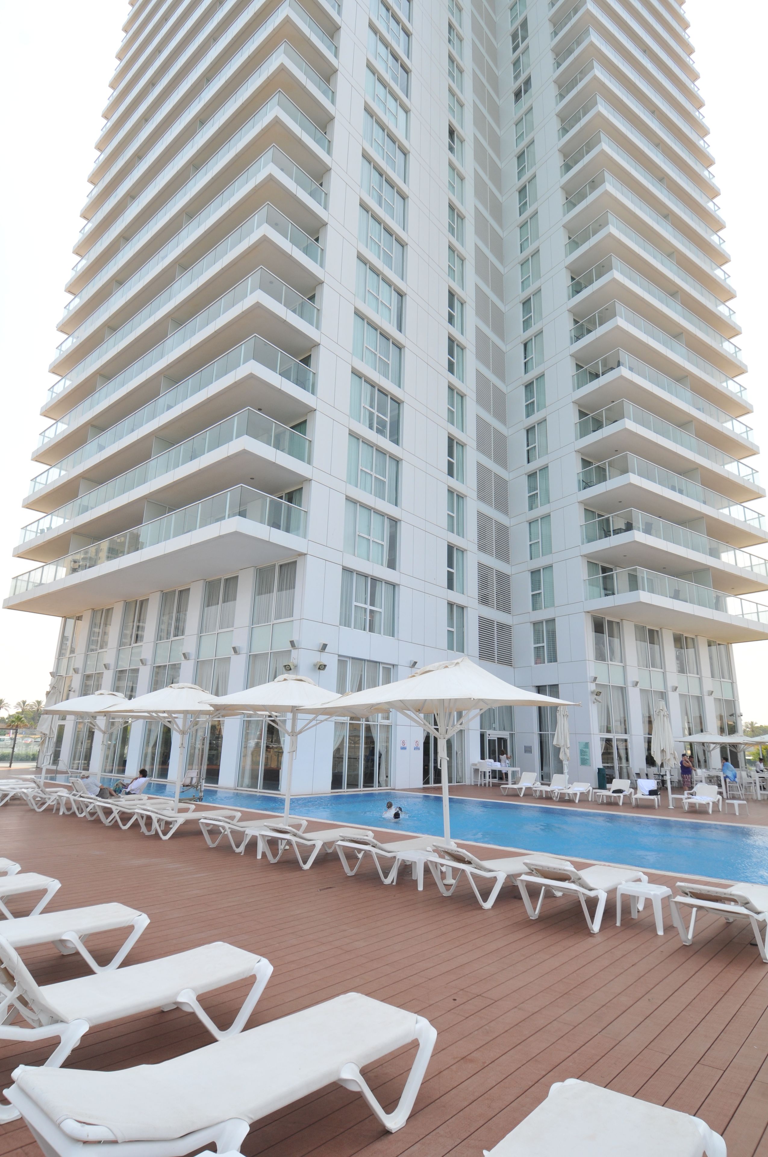 Un hôtel de grande hauteur doté d’une piscine et de chaises longues.