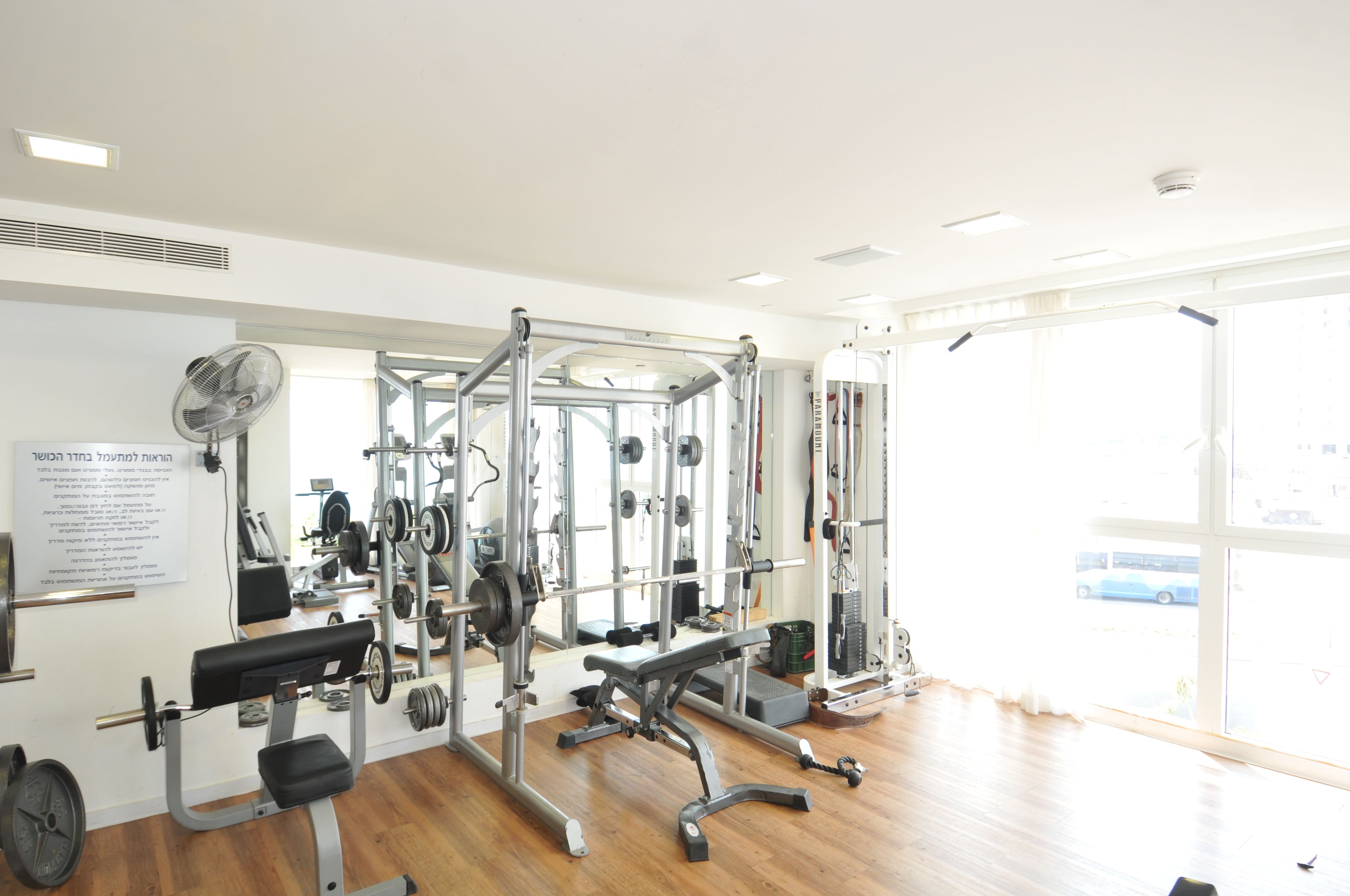 A gym with various exercise equipment, a bench, and a mirror.