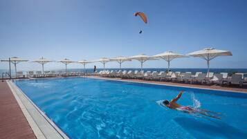 Relax by the pool with ocean views, surrounded by sun loungers and umbrellas.