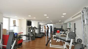 A gym with various exercise equipment, a red bench, and a weight rack.