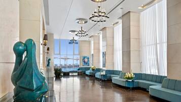 A spacious lobby with a modern design, featuring a large seating area, a sculpture, and artwork on the walls.
