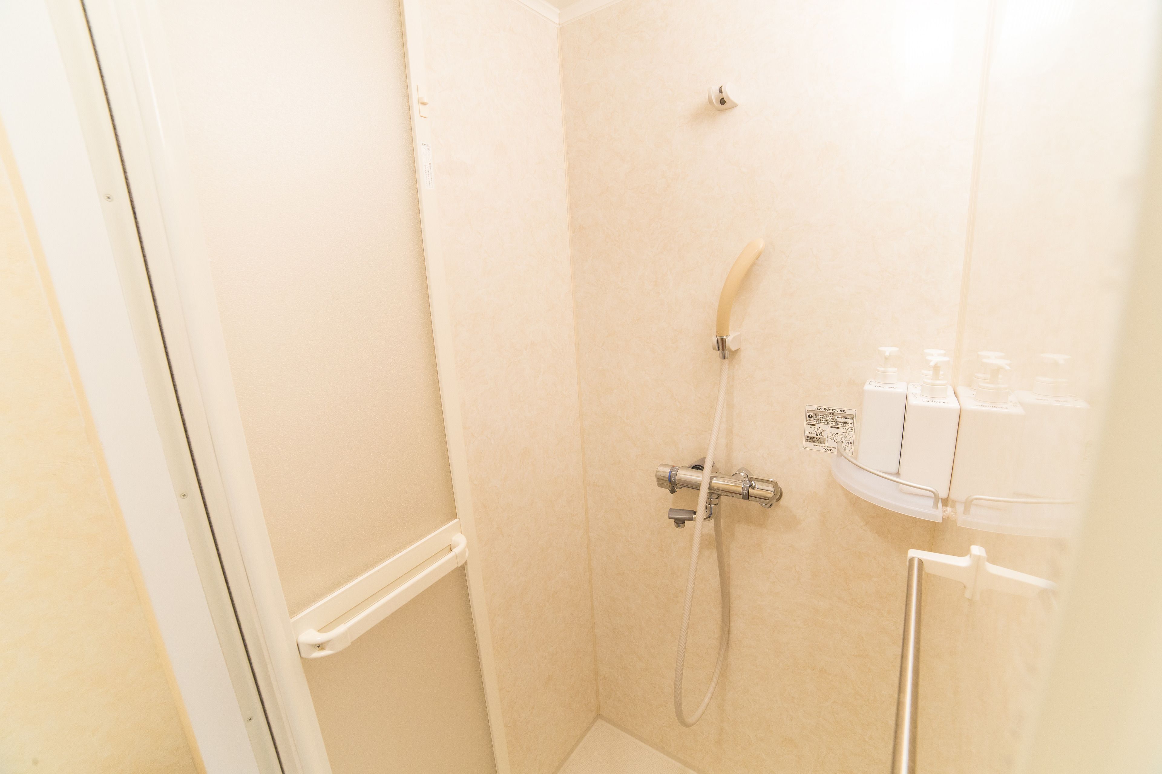 A small, enclosed shower area with a handheld showerhead and a wall-mounted faucet.