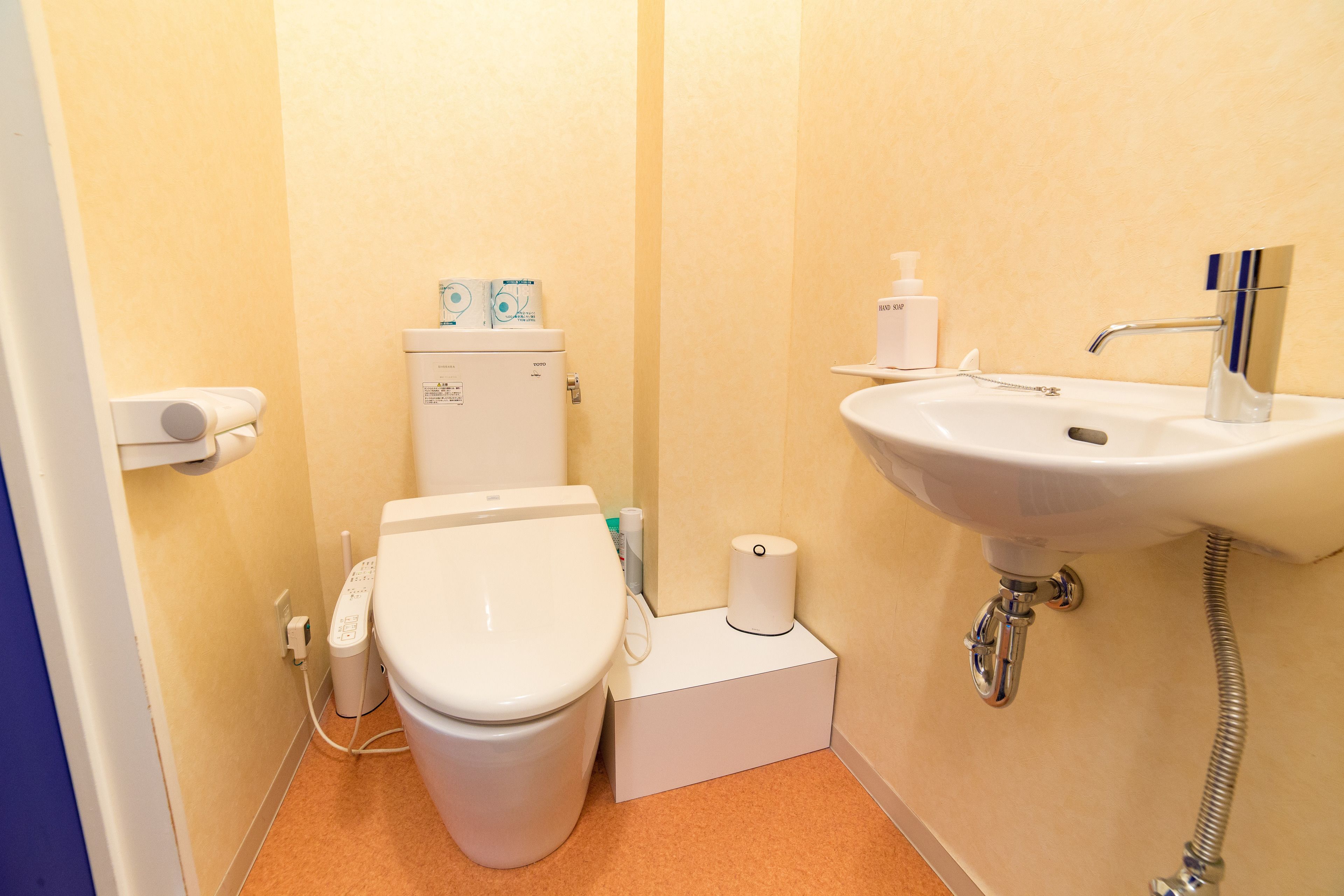 Un baño pequeño con inodoro, lavamanos y soporte para papel higiénico.