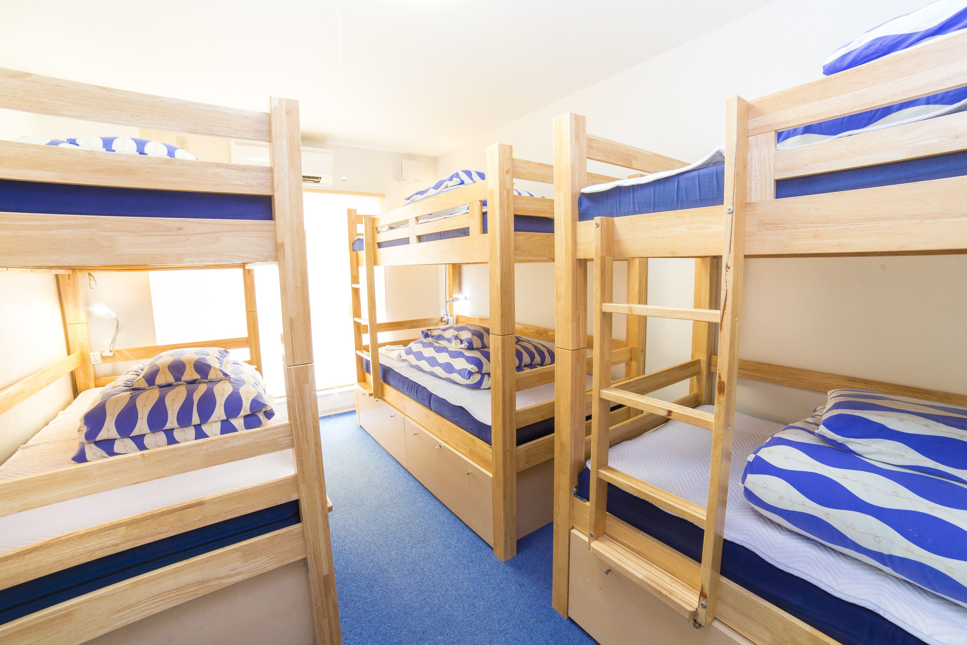 Une chambre avec trois lits superposés, chacun étant équipé de draps bleus et blancs.