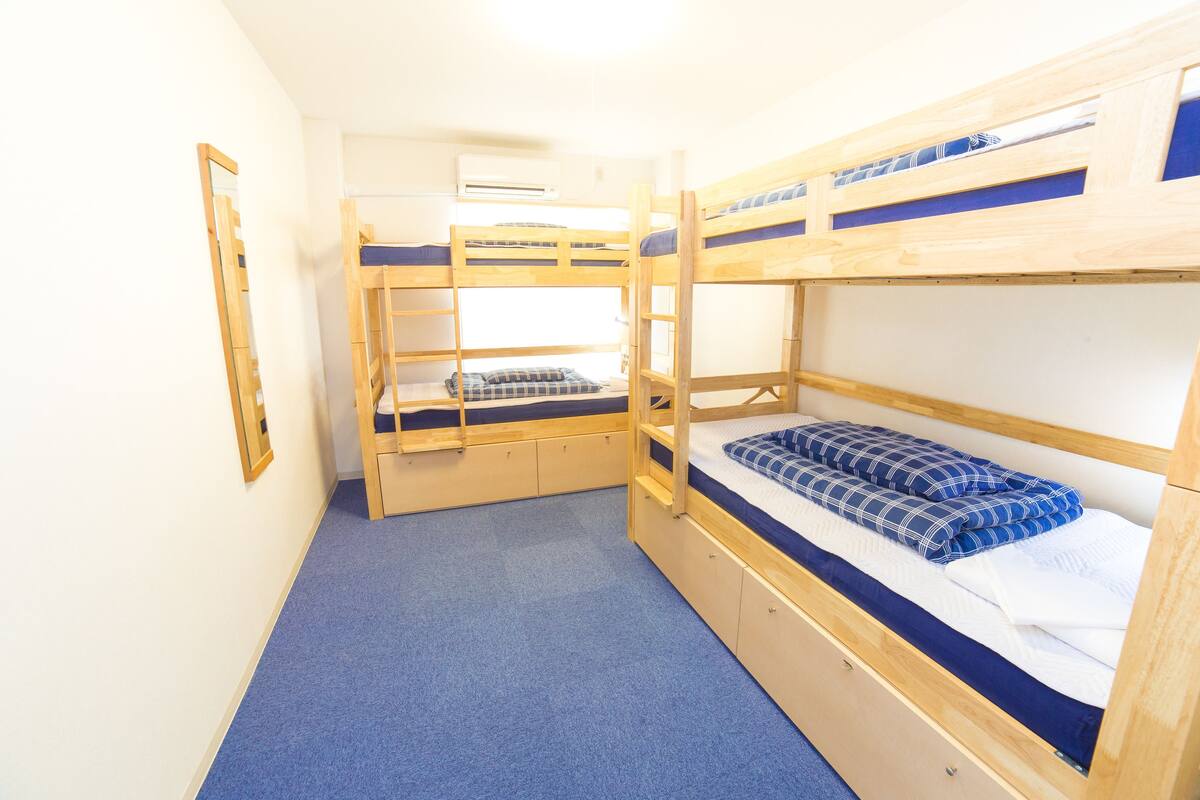 A bunk bed room with a blue carpet, wooden bunk beds, and a mirror on the wall.