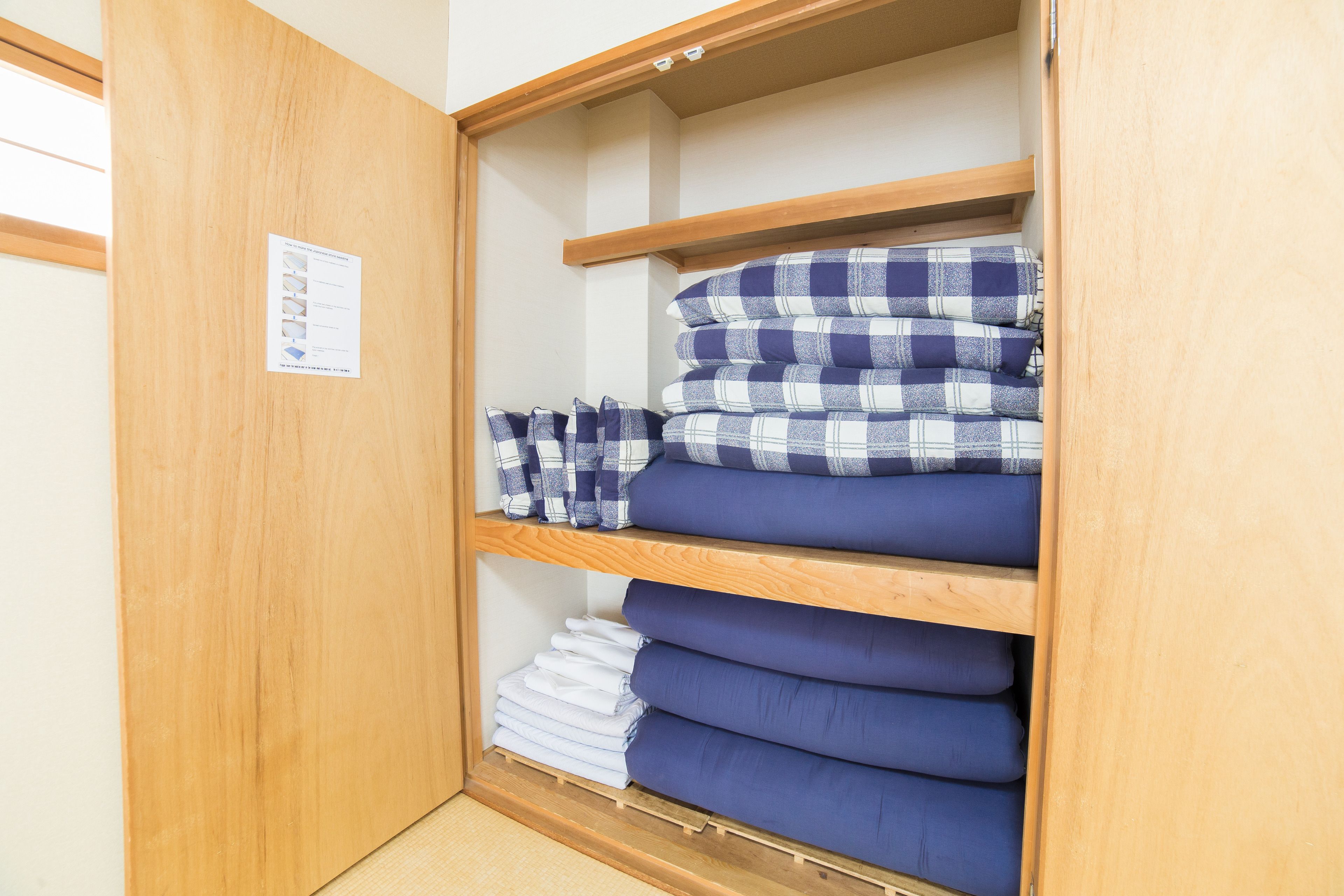 A storage area with shelves holding folded bedding items.