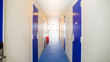 A long, narrow hallway with blue carpet, beige walls, and blue doors.