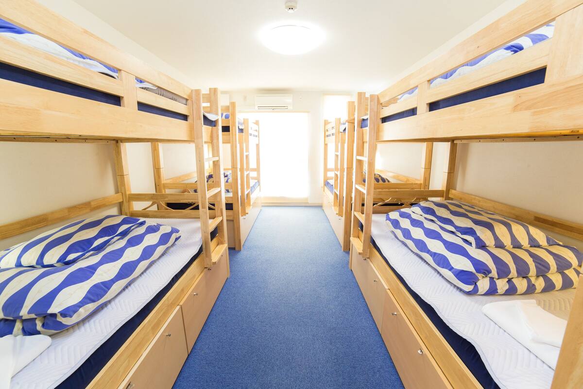 A room with bunk beds, a blue carpet, and a white door.