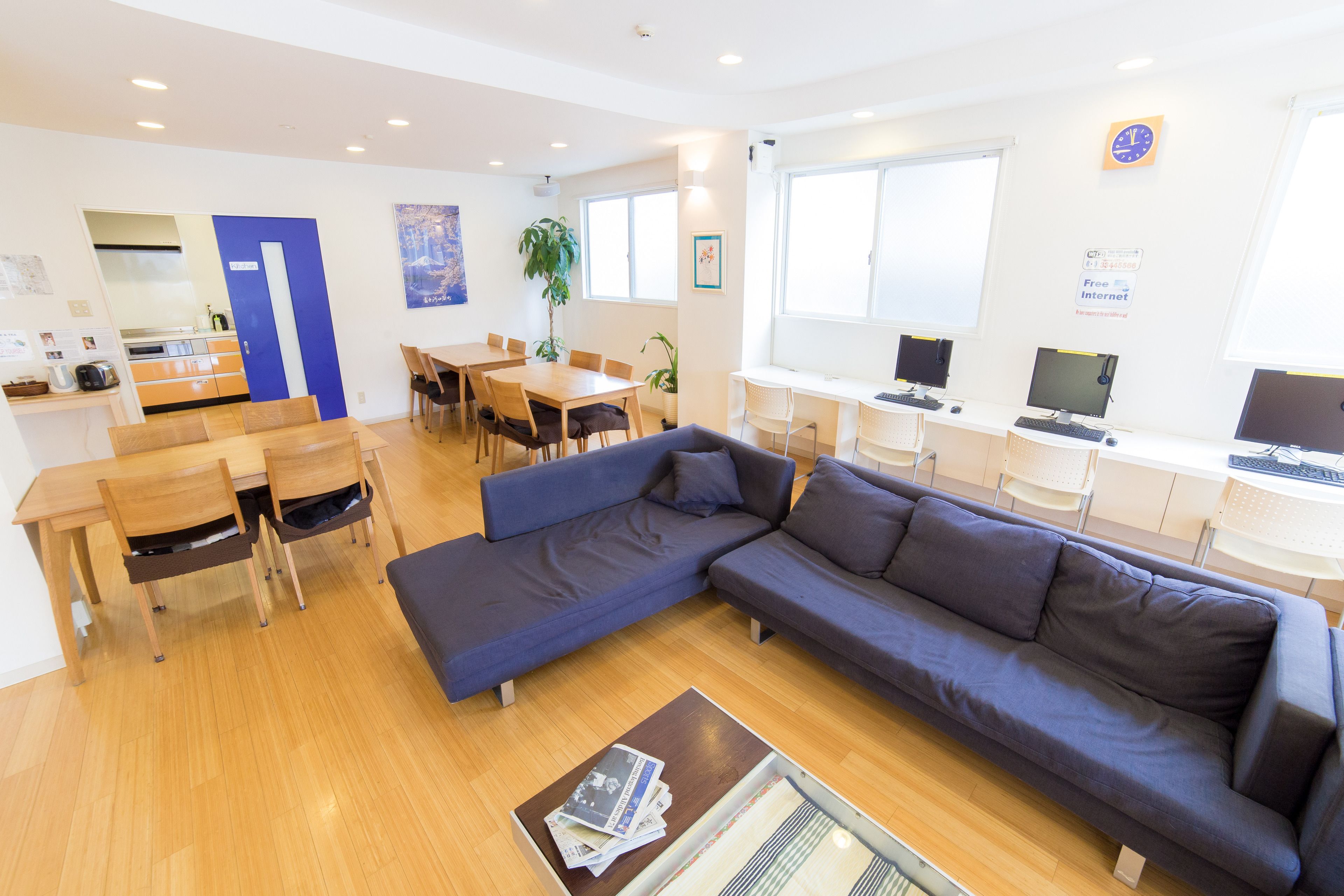 A modern living room with a sofa, dining table, chairs, and a kitchenette.