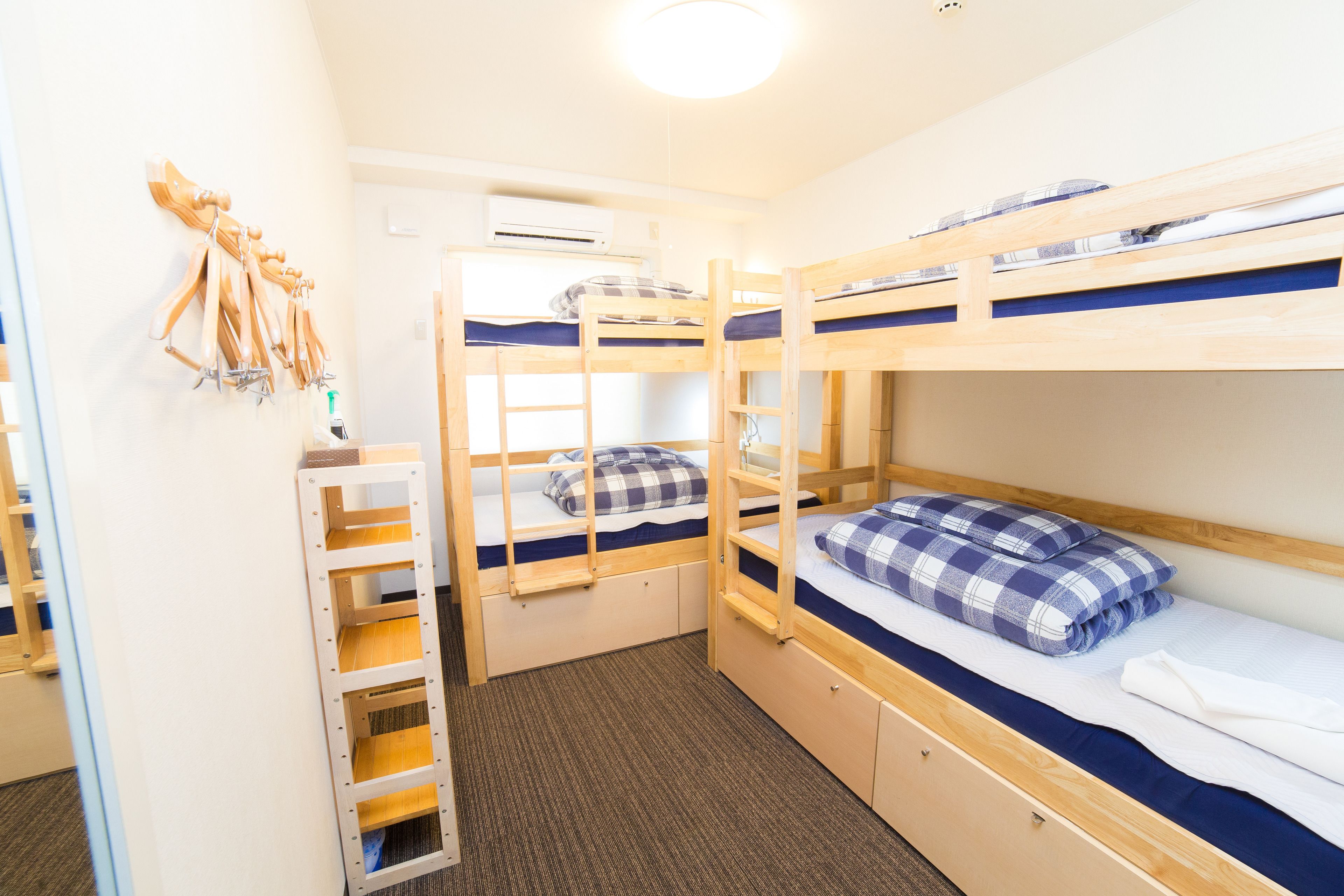 A bunk bed room with a ladder, a small shelf, and an air conditioning unit.