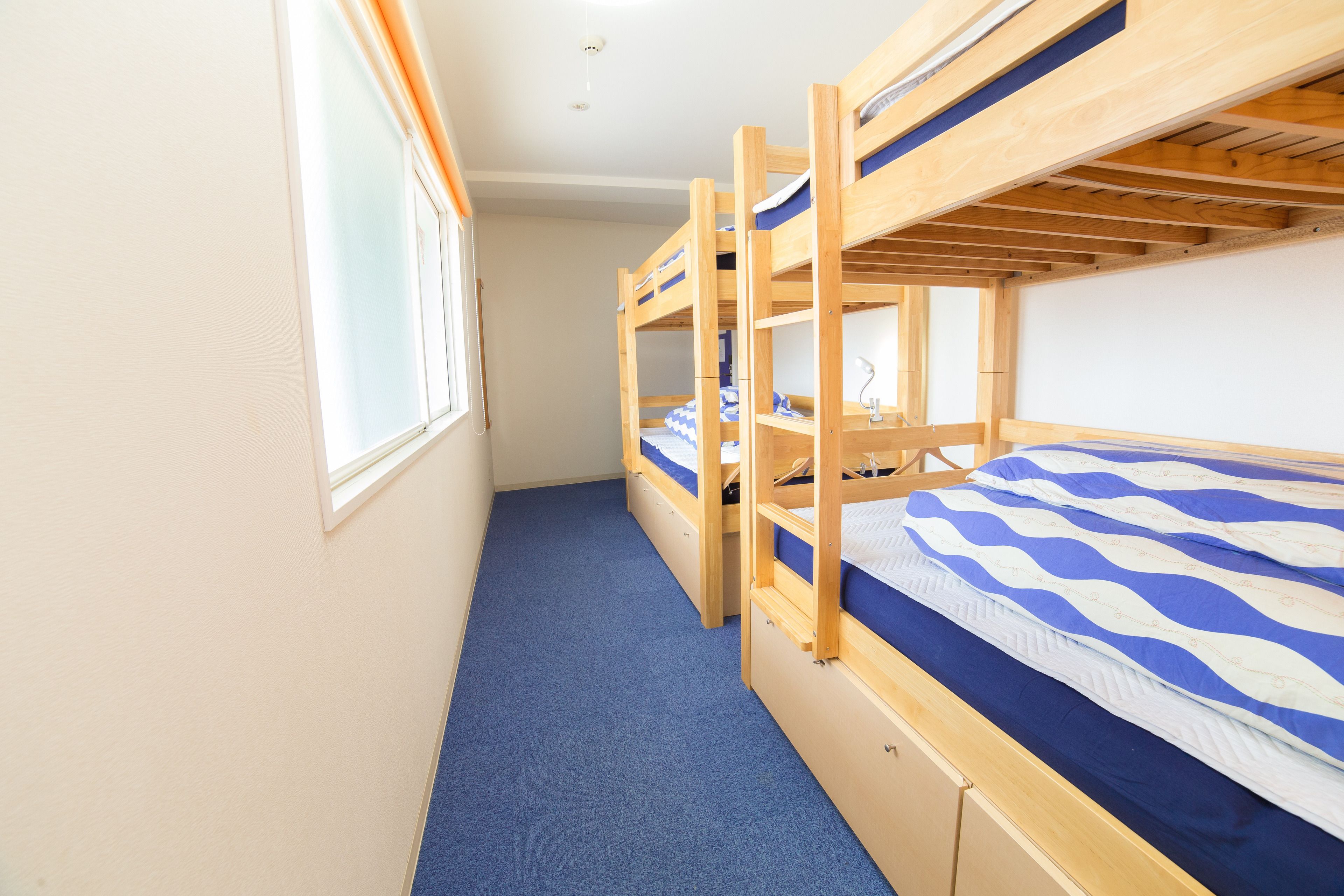 A bunk room with two bunk beds, a window, and a blue carpet.