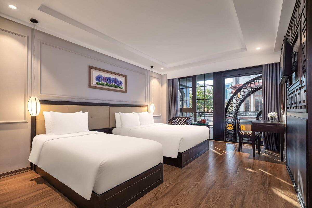 A hotel room with two beds, a large window with a view, and a staircase.