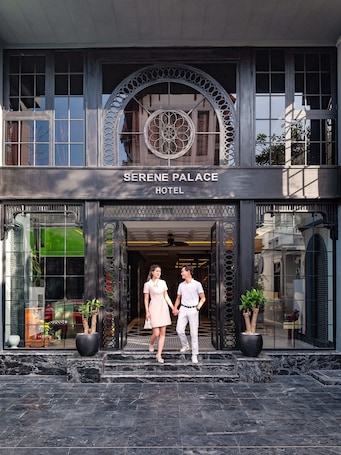 The entrance of Serene Palace Hotel with a modern design, featuring a large arched window and a sign above the entrance.
